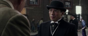 Movie still from “Mr. Holmes” (2015), directed by Bill Condon – A man in a suit and a top hat standing in front of a crowd of onlookers; Close Up shot, Over the shoulder angle