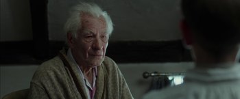 Movie still from “Mr. Holmes” (2015), directed by Bill Condon – An old man with white hair sitting in a room; Close Up shot, Over the shoulder angle