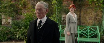 Movie still from “Mr. Holmes” (2015), directed by Bill Condon – An older man and a young woman standing next to each other; Medium shot, Over the shoulder angle