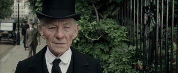 Movie still from “Mr. Holmes” (2015), directed by Bill Condon – An older man wearing a top hat and a suit; Close Up shot, Over the shoulder angle