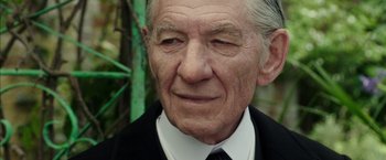Movie still from “Mr. Holmes” (2015), directed by Bill Condon – An older man wearing a black suit and white shirt; Close Up shot, Low angle