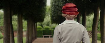 Movie still from “Mr. Holmes” (2015), directed by Bill Condon – A woman wearing a red hat standing in a park; Close Up shot, Over the shoulder angle