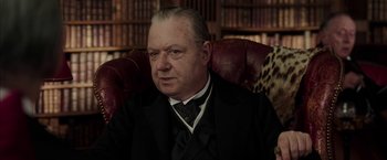 Movie still from “Mr. Holmes” (2015), directed by Bill Condon – An older man wearing a suit and tie in a library; Close Up shot, Low angle