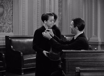 Movie still from “Mr. Smith Goes to Washington” (1939), directed by Frank Capra – A man helping another man put on a bow tie; Medium shot, Over the shoulder angle