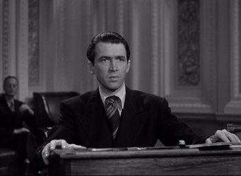 Movie still from “Mr. Smith Goes to Washington” (1939), directed by Frank Capra – A black and white photo of a man sitting at a desk; Medium shot, Low angle