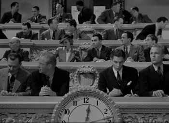 Movie still from “Mr. Smith Goes to Washington” (1939), directed by Frank Capra – A group of people sitting in front of a large clock; Wide shot, High angle