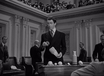 Movie still from “Mr. Smith Goes to Washington” (1939), directed by Frank Capra – A man in a suit and tie in front of a court room; Medium shot, High angle