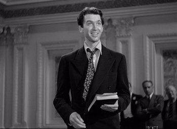 Movie still from “Mr. Smith Goes to Washington” (1939), directed by Frank Capra – A man in a suit and tie holding a book; Medium shot, Low angle