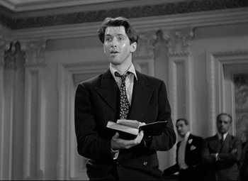 Movie still from “Mr. Smith Goes to Washington” (1939), directed by Frank Capra – A black and white photo of a man in a suit holding a book; Medium shot, Low angle
