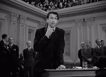 Movie still from “Mr. Smith Goes to Washington” (1939), directed by Frank Capra – A black and white photo of a man standing at a podium; Medium shot, Low angle