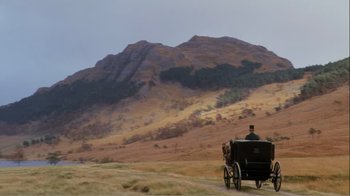 Movie still from “Mrs. Brown” (1997), directed by John Madden – A horse drawn carriage traveling down a dirt road near a mountain; Extreme Wide shot, Low angle