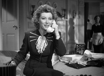 Movie still from “Mrs. Miniver” (1942), directed by William Wyler – A woman sitting on a bed talking on a phone; Medium shot, Low angle