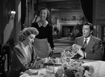 Movie still from “Mrs. Miniver” (1942), directed by William Wyler – A group of people sitting at a table eating food; Medium shot, Over the shoulder angle