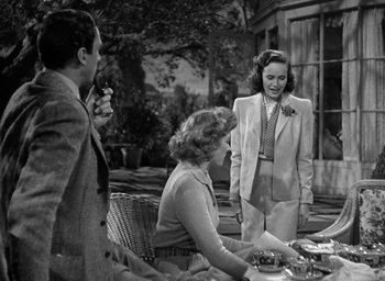 Movie still from “Mrs. Miniver” (1942), directed by William Wyler – Two women and a man standing at an outdoor table; Medium shot, Over the shoulder angle