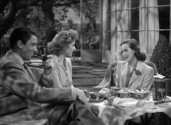 Movie still from “Mrs. Miniver” (1942), directed by William Wyler – A group of people sitting around a table; Medium shot, High angle