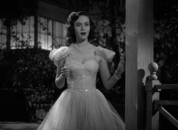 Movie still from “Mrs. Miniver” (1942), directed by William Wyler – A black and white photo of a woman in a dress; Medium shot, Low angle