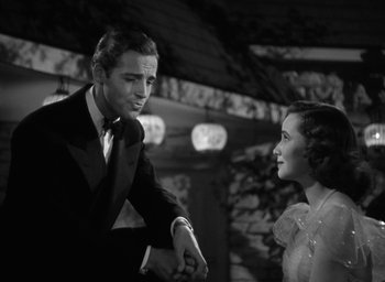 Movie still from “Mrs. Miniver” (1942), directed by William Wyler – A black and white photo of a man and a woman shaking hands; Medium shot, Low angle