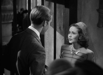 Movie still from “Mrs. Miniver” (1942), directed by William Wyler – A man and a woman are talking to each other; Medium shot, Over the shoulder angle