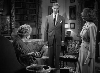 Movie still from “Mrs. Miniver” (1942), directed by William Wyler – A man standing next to two women in a living room; Medium shot, Low angle
