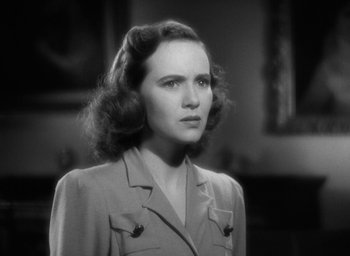 Movie still from “Mrs. Miniver” (1942), directed by William Wyler – A woman in a suit is standing in a room; Close Up shot, Low angle