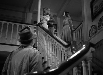 Movie still from “Mrs. Miniver” (1942), directed by William Wyler – Two women and a man standing at the bottom of a staircase; Wide shot, Low angle