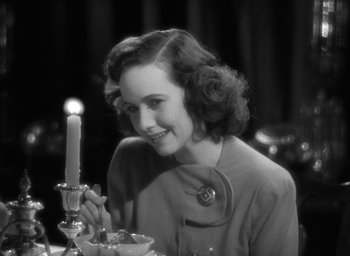 Movie still from “Mrs. Miniver” (1942), directed by William Wyler – A woman sitting at a table with a lit candle; Close Up shot, Over the shoulder angle