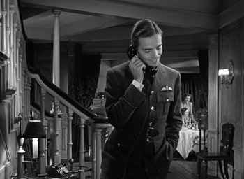 Movie still from “Mrs. Miniver” (1942), directed by William Wyler – A man in a suit and tie talking on a phone; Medium shot, Low angle