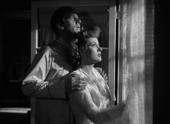 Movie still from “Mrs. Miniver” (1942), directed by William Wyler – A man and a woman standing next to each other near a window; Medium shot, Low angle