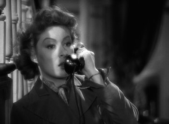 Movie still from “Mrs. Miniver” (1942), directed by William Wyler – A woman talking on a phone while wearing a suit and tie; Close Up shot, Low angle