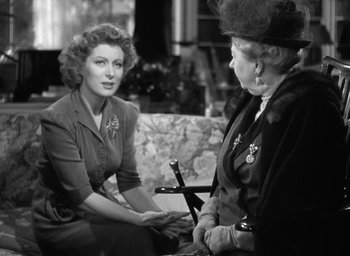 Movie still from “Mrs. Miniver” (1942), directed by William Wyler – Two women sitting on a couch talking to each other; Medium shot, Over the shoulder angle