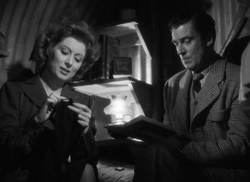 Movie still from “Mrs. Miniver” (1942), directed by William Wyler – A man and a woman are looking at a book; Medium shot, Low angle