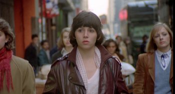 Movie still from “Ms .45” (1981), directed by Abel Ferrara – A woman in a brown leather jacket standing on a sidewalk; Close Up shot, Over the shoulder angle