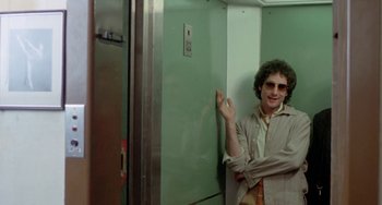 Movie still from “Ms .45” (1981), directed by Abel Ferrara – A man standing in front of an elevator smiling for the camera; Medium shot, Low angle