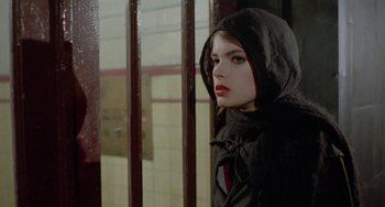 Movie still from “Ms .45” (1981), directed by Abel Ferrara – A woman wearing a hooded jacket standing in front of a window; Close Up shot, Over the shoulder angle