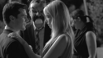 Movie still from “Much Ado About Nothing” (2012), directed by Joss Whedon – A man and a woman are holding hands in front of a crowd; Close Up shot, Over the shoulder angle