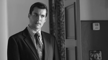 Movie still from “Much Ado About Nothing” (2012), directed by Joss Whedon – Black and white photograph of a man wearing a suit and tie; Close Up shot, Over the shoulder angle