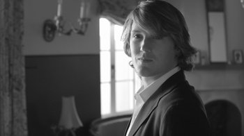 Movie still from “Much Ado About Nothing” (2012), directed by Joss Whedon – Black and white photograph of a man in a suit; Close Up shot, Low angle
