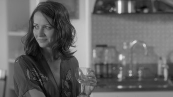 Movie still from “Much Ado About Nothing” (2012), directed by Joss Whedon – A woman holding a wine glass in her right hand; Close Up shot, Over the shoulder angle