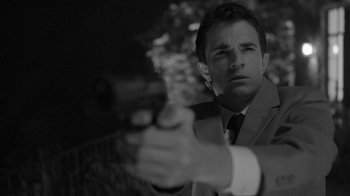 Movie still from “Much Ado About Nothing” (2012), directed by Joss Whedon – A black and white photo of a man holding a gun; Close Up shot, Low angle
