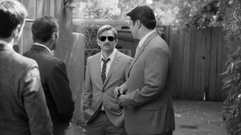 Movie still from “Much Ado About Nothing” (2012), directed by Joss Whedon – A man in a suit standing next to another man in a suit; Medium shot, Over the shoulder angle