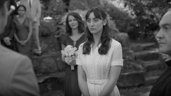 Movie still from “Much Ado About Nothing” (2012), directed by Joss Whedon – Two women standing next to each other in front of trees; Medium shot, Over the shoulder angle