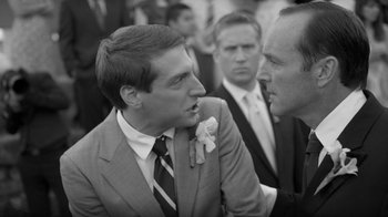 Movie still from “Much Ado About Nothing” (2012), directed by Joss Whedon – A man in a suit and tie talking to another man in a suit and tie; Close Up shot, Over the shoulder angle