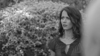 Movie still from “Much Ado About Nothing” (2012), directed by Joss Whedon – Black and white photograph of a woman in front of a bush; Close Up shot, Over the shoulder angle