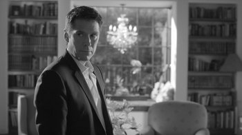 Movie still from “Much Ado About Nothing” (2012), directed by Joss Whedon – A black and white photo of a man in a suit; Medium shot, Low angle