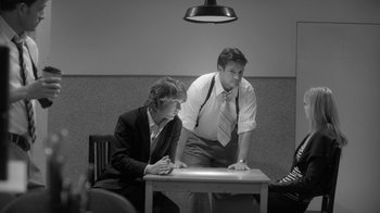 Movie still from “Much Ado About Nothing” (2012), directed by Joss Whedon – A man and a woman sitting at a table looking at something; Medium shot, Over the shoulder angle