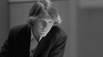 Movie still from “Much Ado About Nothing” (2012), directed by Joss Whedon – Black and white photograph of a young man in a suit; Close Up shot, Low angle