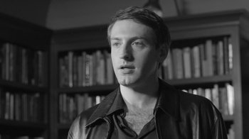 Movie still from “Much Ado About Nothing” (2012), directed by Joss Whedon – Black and white photograph of a young man in front of bookshelves; Close Up shot, Low angle