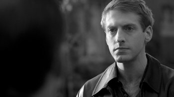 Movie still from “Much Ado About Nothing” (2012), directed by Joss Whedon – Black and white photograph of a young man looking at the camera; Close Up shot, Over the shoulder angle