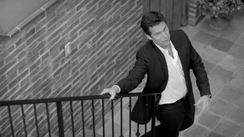 Movie still from “Much Ado About Nothing” (2012), directed by Joss Whedon – A black and white photo of a man leaning on a railing; Medium shot, High angle