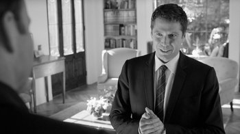 Movie still from “Much Ado About Nothing” (2012), directed by Joss Whedon – Black and white photograph of a man wearing a suit and tie; Medium shot, Over the shoulder angle